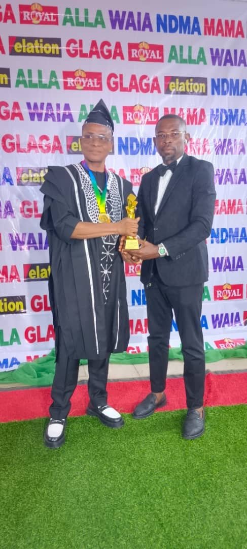 A trophy presentation in front of the sponsor backdrop at the West Africa Icon Award ceremony in Abuja